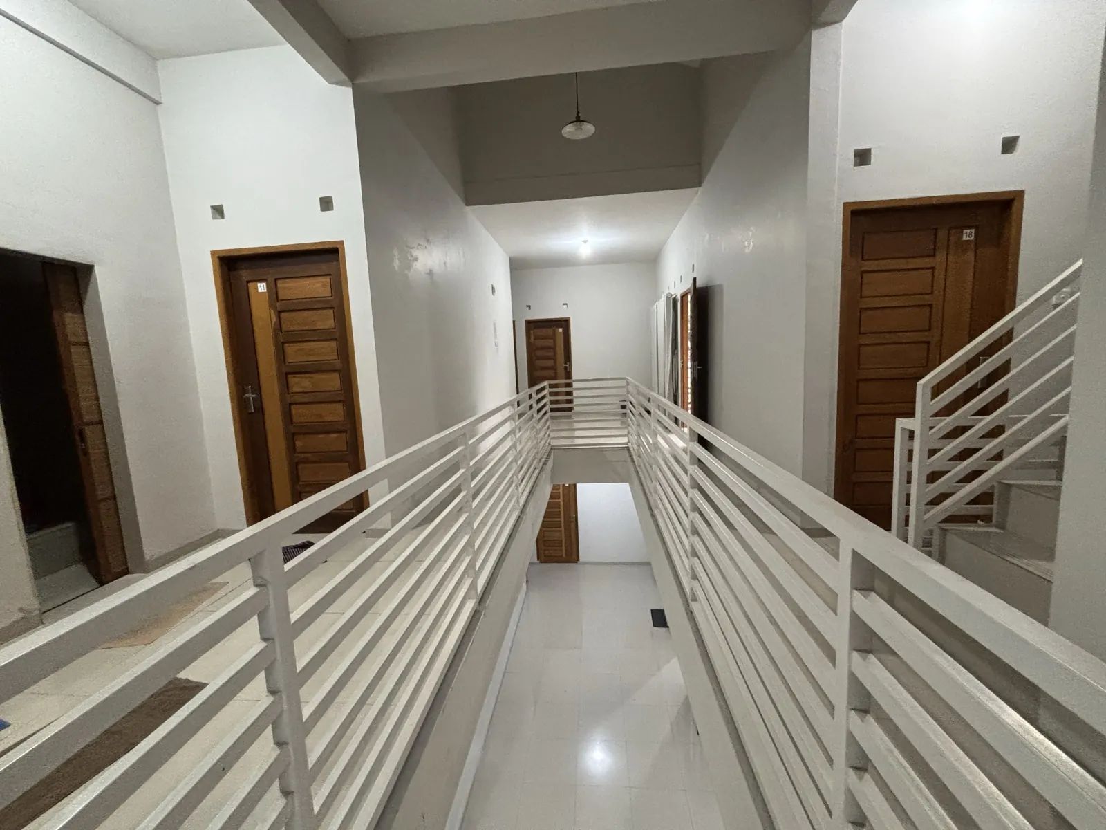 Upper-floor corridor with a railing and room doors