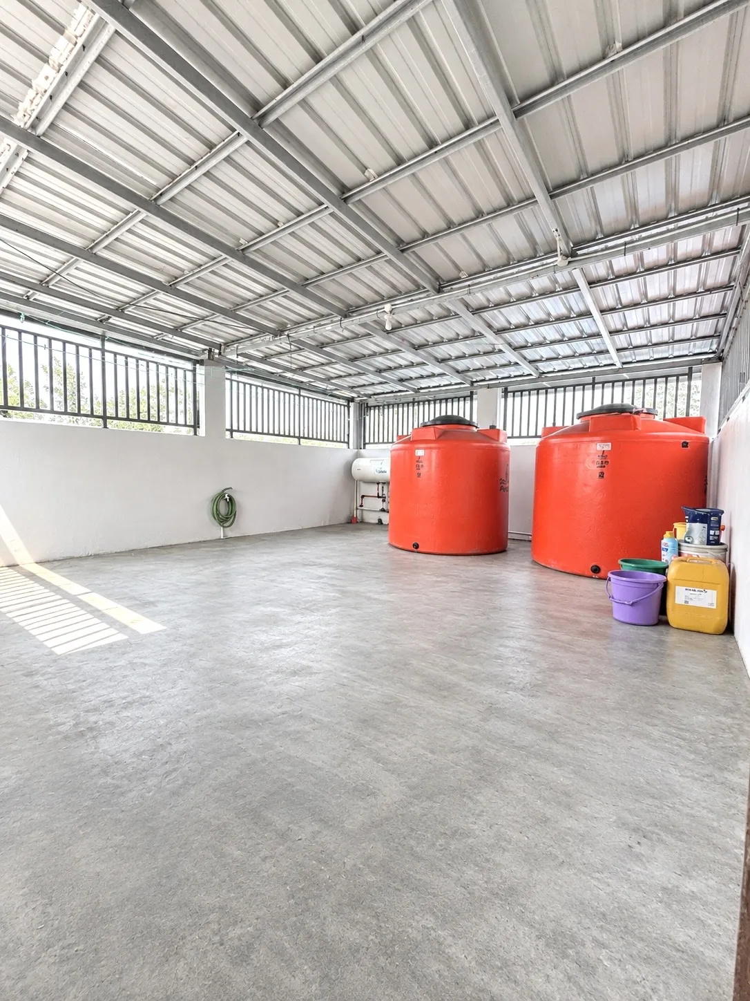Covered rooftop area with water tanks and open floor space